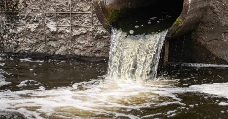 Dirty water flows from the pipe into the river, environmental pollution. Sewerage, treatment facilities